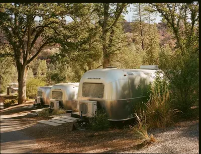 a row of three trailers parked in a parking lot at AutoCamp Yosemite in Midpines