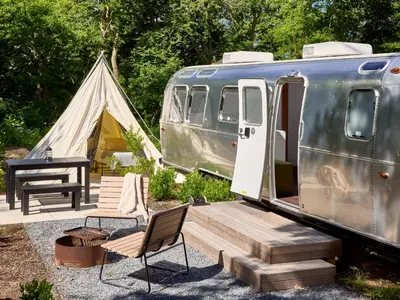 a tent and a table and chairs next to a trailer at AutoCamp Yosemite in Midpines