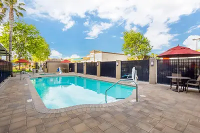 a swimming pool with a patio and a table at Best Western Plus Villa Del Lago Inn Patterson in Patterson