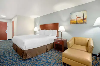 a hotel room with a bed and a chair at Best Western Plus Villa Del Lago Inn Patterson in Patterson