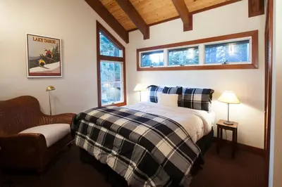 a bedroom with a bed and a chair and two windows at Luxury Lodgepole Home at Northstar in Truckee
