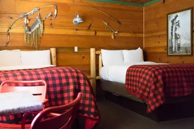 a room with two beds and a table and chairs at Shaver Lake Village Hotel in Shaver Lake