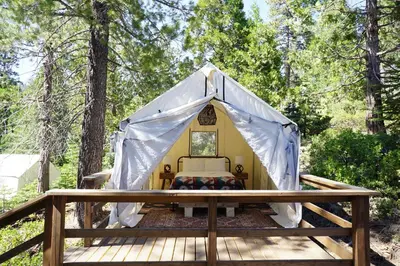 a bed in a tent on a wooden deck at Shaver Lake Village Hotel in Shaver Lake