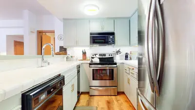 a kitchen with white cabinets and a stainless steel refrigerator at Snowcreek 887 Condo in Mammoth Lakes
