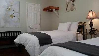 a bedroom with two beds with white sheets and a lamp at El Rancho Motel in Bishop
