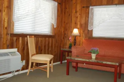 a living room with a couch and a table and two windows at El Rancho Motel in Bishop