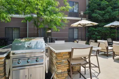 a outdoor grill and table with chairs and umbrellas at Homewood Suites by Hilton Fresno in Fresno