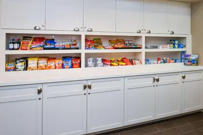 a pantry with white cabinets and shelves filled with food at Homewood Suites by Hilton Fresno in Fresno