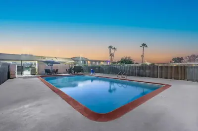 a swimming pool in a yard with a fence at Studio 6 Suites Madera, CA Yosemite in Madera
