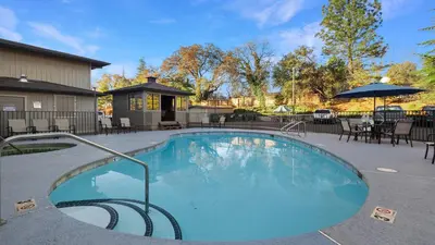 a large swimming pool with chairs and an umbrella at Sonora Aladdin Motor Inn in Sonora