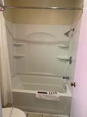 a bathroom with a white tub and a toilet at Holiday Motel Oakdale in Oakdale
