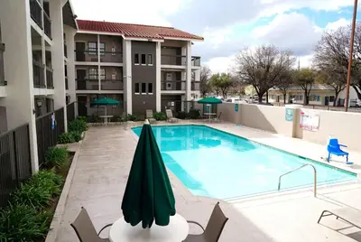 a swimming pool with an umbrella next to a building at La Quinta Inn by Wyndham Fresno Yosemite in Fresno