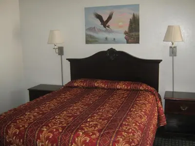 a bedroom with a bed with two lamps and a painting at Jamestown Railtown Motel in Jamestown