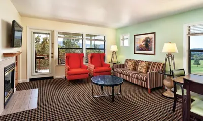 a living room with a couch and two red chairs at WorldMark Angels Camp in Angels Camp