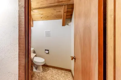 a bathroom with a toilet and a wooden door at Pine Paradise in Camp Connell