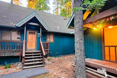 a blue house with a wooden door and a tree at Pine Paradise in Camp Connell