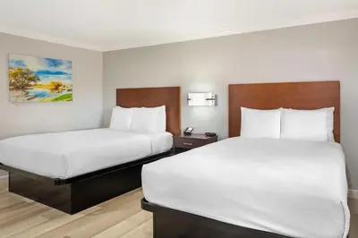 two beds in a hotel room with white sheets at Best Western Inn in Merced