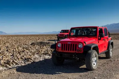 two red jeepneys parked on a dirt road at The Inn at Death Valley in Death Valley