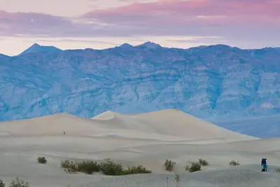 a person standing on a sand dune in front of mountains at The Inn at Death Valley in Death Valley