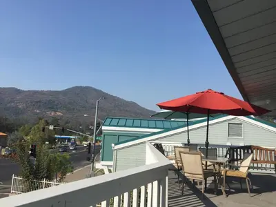 a patio with a table and a red umbrella at Oakhurst Lodge in Oakhurst