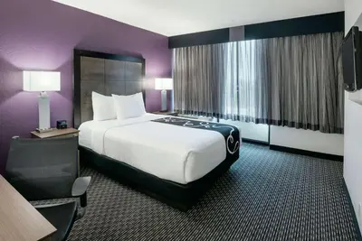 a hotel room with a large bed and purple walls at La Quinta by Wyndham Rancho Cordova Sacramento in Rancho Cordova