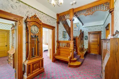 a living room with a grandfather clock and stairs at Lodi Hill House in Lodi