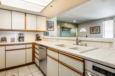 a kitchen with white cabinets and a sink at Bridges 107 in Mammoth Lakes