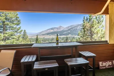 a bar with stools and a bottle of wine on a porch with mountains at Bridges 107 in Mammoth Lakes