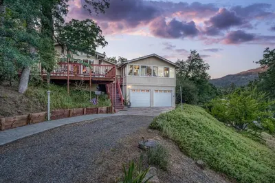 a large house with a garage on a hill at A Bed of Roses in Yosemite Forks
