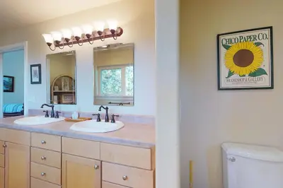 a bathroom with two sinks and a sunflower sign on the wall at Pine Mountain Getaway (02-461) in Groveland