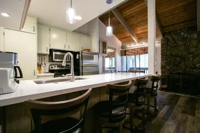 a kitchen with a counter with a sink and bar stools at Sunshine Village 104 Condo in Mammoth Lakes