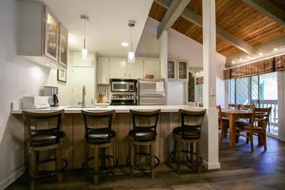a kitchen with a bar with stools and a counter top at Sunshine Village 104 Condo in Mammoth Lakes