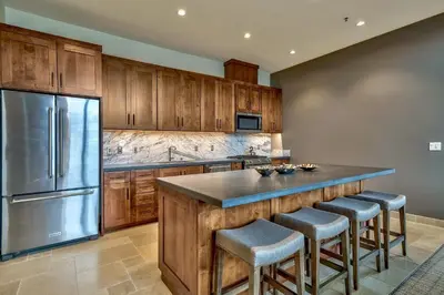 a kitchen with wooden cabinets and a stainless steel refrigerator at Luxury Three Bedroom Residence Steps From Heavenly Village Condo in South Lake Tahoe