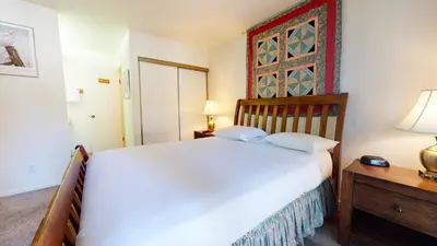 a bedroom with a white bed and a wooden nightstand at Summit Condominium #273 Condo in Mammoth Lakes