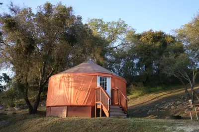 an orange yurt on a hill with trees at Yosemite RV Resort in Coarsegold