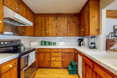 a kitchen with wooden cabinets and white counter tops at Heart's Desire on the Lake (01-275) in Groveland