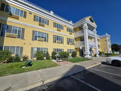 a yellow apartment building with a car parked in front of it at Quality Inn & Suites Tulare in Tulare