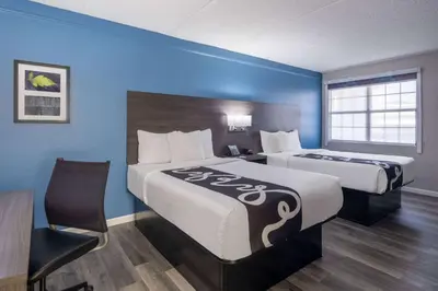 a hotel room with two beds and a chair at La Quinta Inn by Wyndham Sacramento North in Sacramento