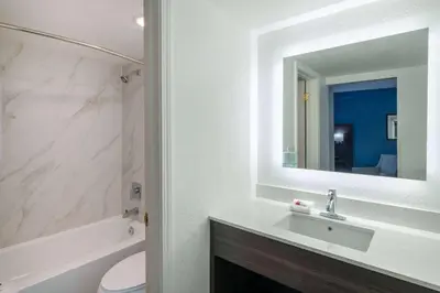 a bathroom with a sink and a toilet and a mirror at La Quinta Inn by Wyndham Sacramento North in Sacramento