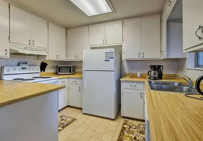 a kitchen with white cabinets and a white refrigerator at NEW! Cozy & Secluded House w/Deck - Near Yosemite! in Tuolumne