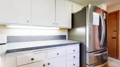 a kitchen with white cabinets and a stainless steel refrigerator at Snowcreek 880 Condo in Mammoth Lakes