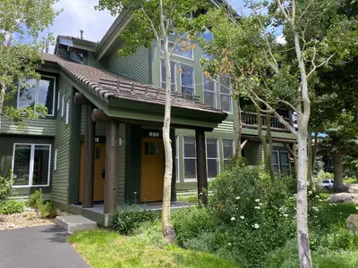 a green house with a porch and trees at Snowcreek 880 Condo in Mammoth Lakes