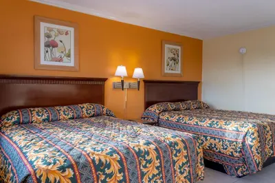 two beds in a hotel room with orange walls at Kings Rest Motel in Lemoore