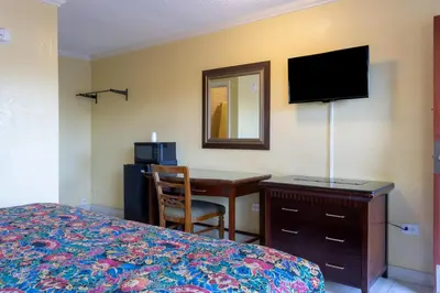 a hotel room with a bed and a desk with a television at Kings Rest Motel in Lemoore