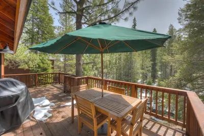 a wooden table with an umbrella on a deck at Serventi Tahoe Donner Cabin in Truckee
