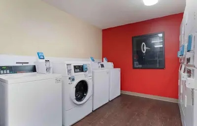 a laundry room with white washing machines and a red wall at Extended Stay America Suites - Sacramento - White Rock Rd in Rancho Cordova