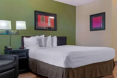 a hotel room with a large bed and a chair at Extended Stay America Suites - Sacramento - Arden Way in Sacramento