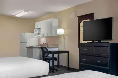 a hotel room with a bed and a desk with a television at Extended Stay America Suites - Sacramento - Arden Way in Sacramento