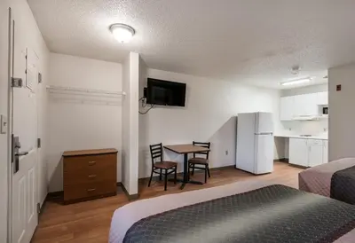 a hotel room with a bed and a table with chairs at HomeTowne Studios by Red Roof Fresno - West in Fresno