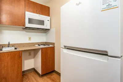 a small kitchen with a refrigerator and a microwave at HomeTowne Studios by Red Roof Fresno - West in Fresno